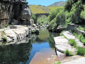 a river with a bridge in the background at La torna in Navarredonda de Gredos