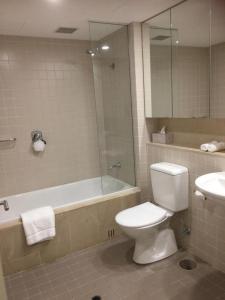 y baño con aseo, ducha y lavamanos. en Beachside Luxury Apartments One & Two Bedroom in Beachfront Oaks Pier Building en Glenelg