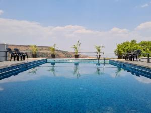 a swimming pool with chairs and a view of the water at Polsburg Panchgani in Panchgani
