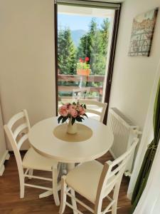 a white table and chairs with a vase of flowers on it at Green Studio in Predeal