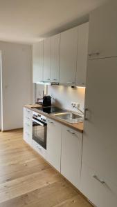 a white kitchen with white cabinets and a sink at Seeblick Apartment in Sankt Gilgen