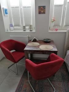 Habitación con 2 sillas rojas y mesa de madera. en La Petite Trier, en Trier