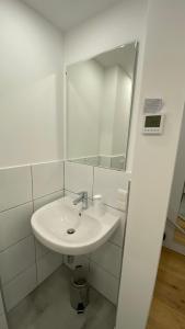 W białej łazience znajduje się umywalka i lustro. w obiekcie Seeblick Apartment w mieście St. Gilgen