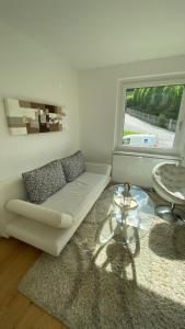 Seeblick Apartment في سانكت جيلجن: غرفة معيشة مع أريكة بيضاء وطاولة زجاجية