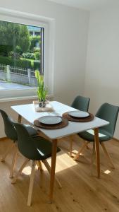 a dining room table with four green chairs around it at Seeblick Apartment in Sankt Gilgen