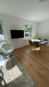 a white living room with a table and a tv at Seeblick Apartment in Sankt Gilgen