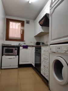 a kitchen with white cabinets and a washer and dryer at Apartamento Puerto Campomanes - Altea in Altea