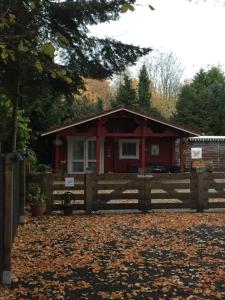 Hegelsom的住宿－Vakantiewoning Hegga，木制围栏后面的红色小屋