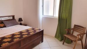 a bedroom with a bed and a chair and a window at Santana single bedroom serviced apartment in Santa Maria