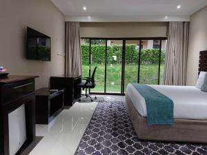 Habitación de hotel con cama, escritorio y TV. en Douglas Lodge & Apartments en Lilongüe