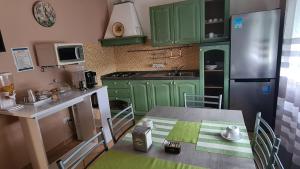 een kleine keuken met groene kasten en een tafel bij B&B Regina in Busto Arsizio