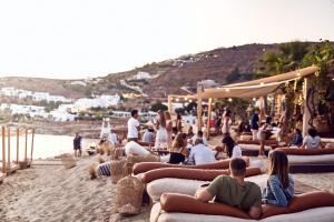 a group of people sitting on the beach at Hippie Chic Hotel in Agios Ioannis Mykonos