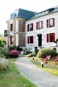un bâtiment avec des chaises rouges devant lui dans l'établissement Hotel Restaurant La Musardiere, à Giverny