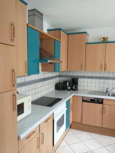 una cocina con armarios de madera y electrodomésticos blancos en Ferienwohnung Madlene 2, en Gablitz