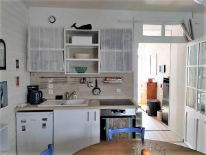 a kitchen with white cabinets and a sink and a table at Ty West in Batz-sur-Mer