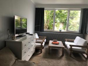 uma sala de estar com uma televisão e um sofá e cadeiras em Spacious studio em Knokke-Heist