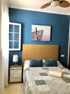 1 dormitorio con una pared azul, 1 cama y ventilador en Mar Azul, en Chiclana de la Frontera