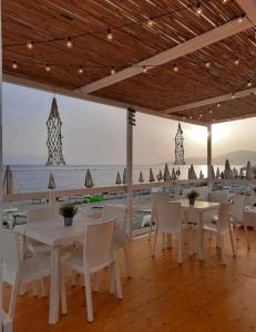 un restaurante con mesas y sillas blancas y el océano en Magicomar Hotel, en Ascea