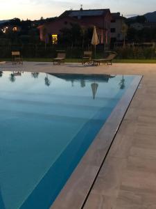 a swimming pool with two benches next to a building at Agriturismo Casa Rosa in Lucca