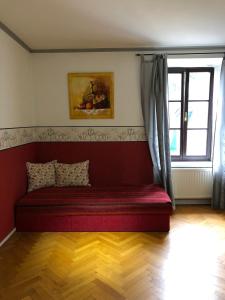 ein rotes Sofa in einem Zimmer mit Fenster in der Unterkunft Ferienwohnung Madlene 2 in Gablitz