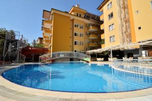 a large blue swimming pool in front of some buildings at Rose Garden Apart Hotel in Alanya