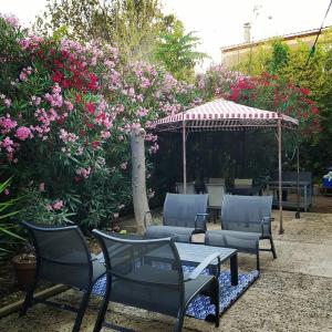 een patio met stoelen, een tafel en een prieel bij La Grangette Grange rénovée 100m2 terrasse privative,10 min mer in Villeveyrac
