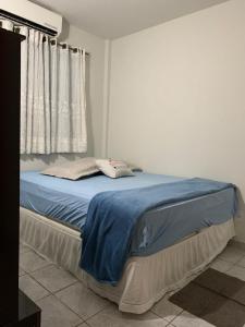um quarto com uma cama com lençóis azuis e uma janela em Apartamento bem localizado próximo ao DETRAN, Assembleia Legislativa de Cuiabá, Centro Político e Shopping Pantanal em Cuiabá