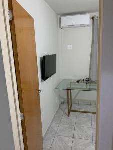 um quarto com uma televisão e uma mesa de vidro em Apartamento bem localizado próximo ao DETRAN, Assembleia Legislativa de Cuiabá, Centro Político e Shopping Pantanal em Cuiabá