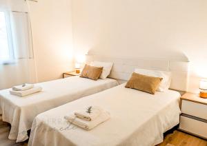 two beds in a room with white walls at Casa Serra São Mamede in Alegrete