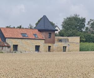 un edificio de ladrillo con un campo delante de él en Le Pigeonnier Spa du Panty Gîte rural de charme, en Saint-Tricat