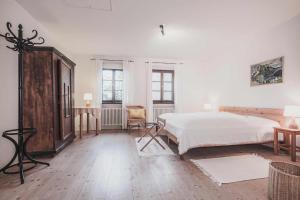 a white bedroom with a bed and a chair at Ferienwohnung Tausendfreund am Chiemsee in Breitbrunn am Chiemsee