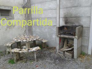 una mesa y un banco junto a un edificio con fogones en Apartamento El Calvario 3, en Tandil 2 fotos más