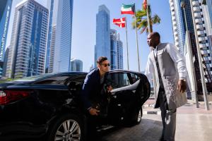 dos hombres están de pie junto a un coche negro en Towers Rotana - Dubai, en Dubái