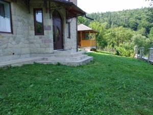 a stone house with a porch and a grass yard at UNDERHILLs house in Yaremche