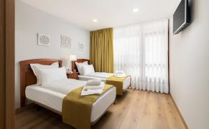 ein Hotelzimmer mit zwei Betten und einem Fernseher in der Unterkunft Asturalqui viviendas turísticas adaptadas in Llueves