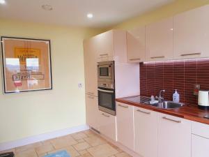 a kitchen with white cabinets and a sink at Seaview Apt in Buncrana with balcony in Buncrana