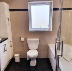 a bathroom with a toilet and a window and a tub at Seaview Apt in Buncrana with balcony in Buncrana