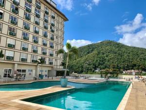 a hotel with a swimming pool in front of a building at Apartamento - Itaipava in Itaipava
