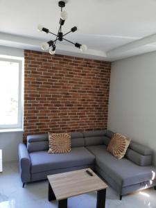a living room with a couch and a brick wall at Lipowa 22 Centrum Apartament in Białystok