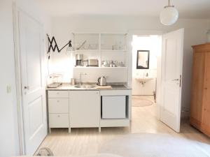 a kitchen with white cabinets and a sink at Ferienstudio-Apartment Tausendfreund "adults only" am Chiemsee in Breitbrunn am Chiemsee