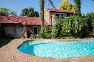 a swimming pool in front of a house at Serene Guest Manor in Johannesburg