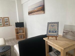 a living room with a couch and a table with a sign at Appartement 2/3 personnes à 10 minutes de Contis plage (Saint Julien en Born) in Saint-Julien-en-Born