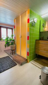 Baño con azulejos verdes y amarillos en la pared en L'eau vive en Ranspach