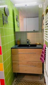 uma cozinha com paredes de azulejos verdes e um lavatório em L'eau vive em Ranspach