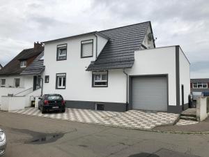 a white house with a car parked in front of it at Özkurt-2 in Friedrichshafen