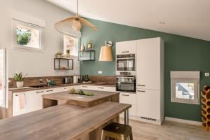 a kitchen with white cabinets and a wooden table at Gîte la Grange du Moulin en Vendée in Saint-Jean-de-Beugné