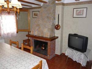 Una sala de estar con chimenea y televisión. en Casa Marcos, en Castellote
