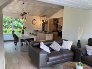 uma sala de estar com um sofá de couro e uma mesa em Chalet des Campanules avec Sauna em Vielsalm