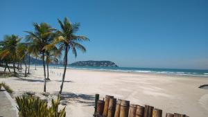 uma praia arenosa com palmeiras e o oceano em Lico Prime - Guarujá no Guarujá