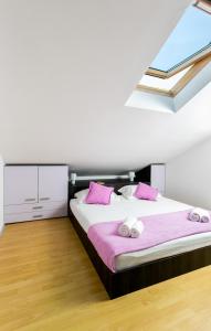 1 dormitorio con 1 cama grande con almohadas rosas en Apartments Marlo, en Dubrovnik